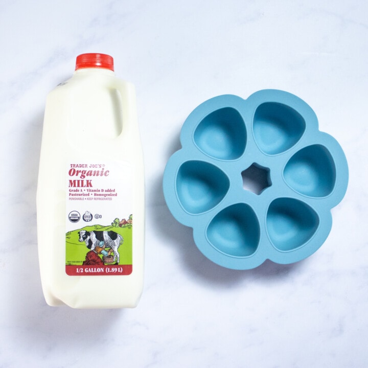 A jug of milk in a freezer tray against a white background.