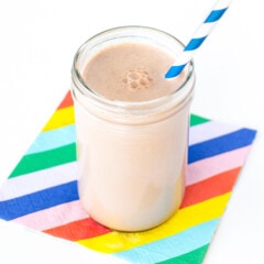 Clear glass full of chocolate milk for kids on a colorful napkin and striped job.