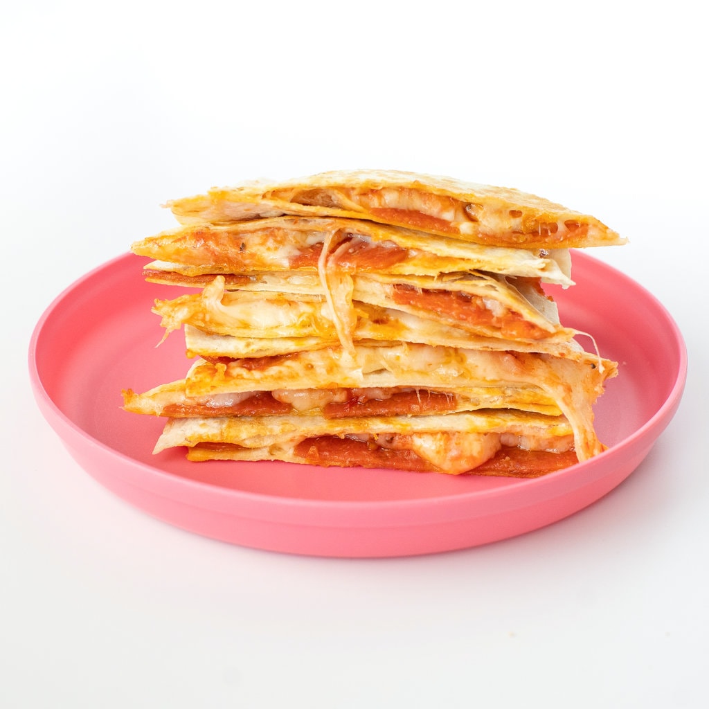 A stack of pizza quesadillas on top of each other on a pink plate with a white background.