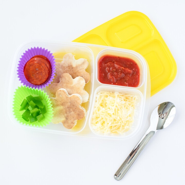 A lunchable for kids that includes pizza crust, shredded cheese, pizza sauce, pepperoni, and green peppers.