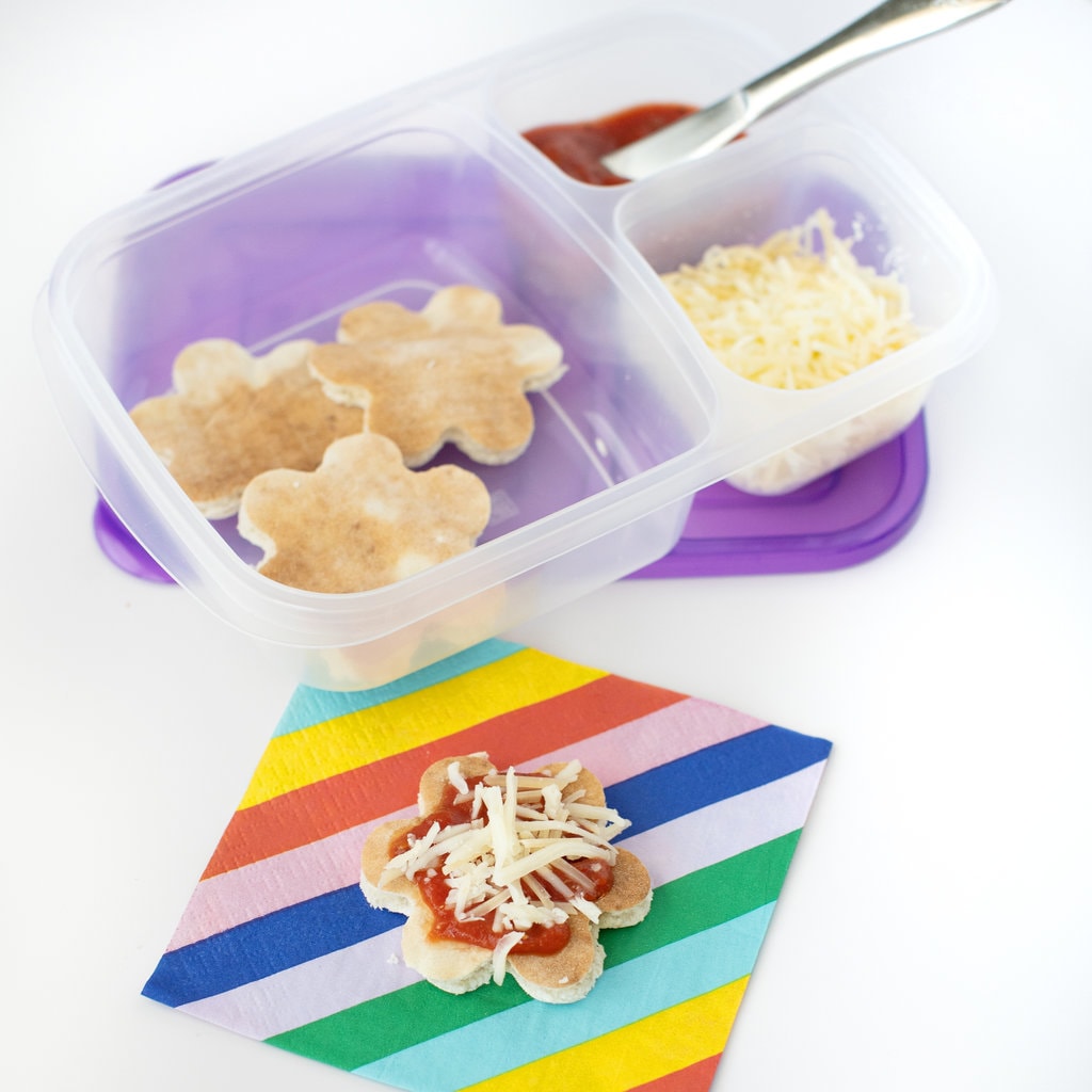 A kids lunch container packs with pizza crust, shredded cheese, and tomato sauce to make homemade pizza for lunchables.