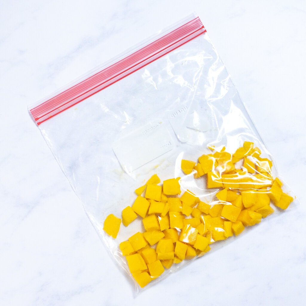 A bag full of mango chunks ready to be frozen.