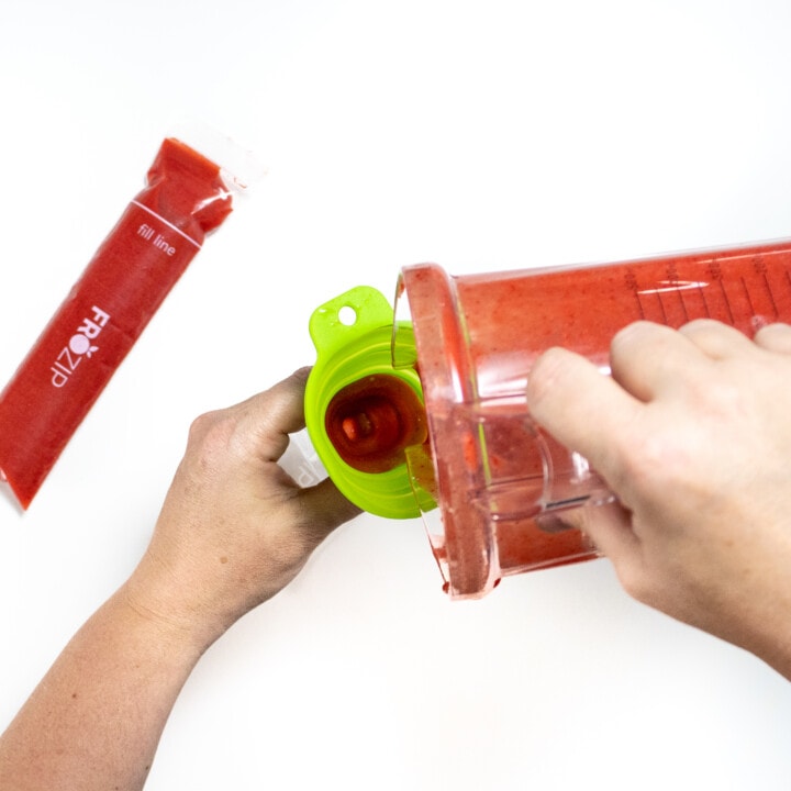 Hans pouring strawberry purée in the freezer, pop tubes against a white background.