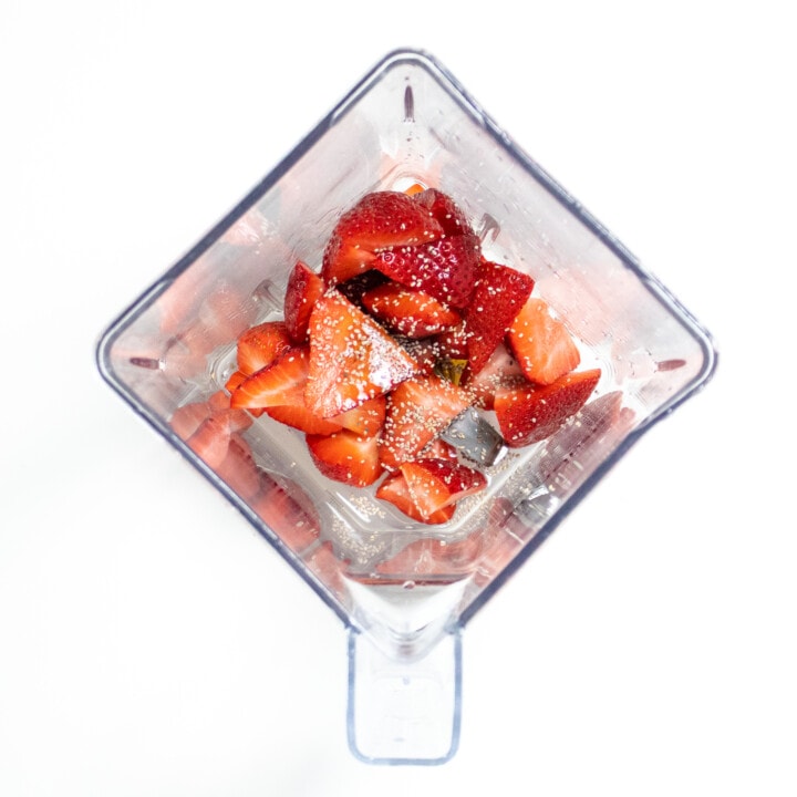 Clear blender full of strawberries, watermelon and chia seeds for popsicles.
