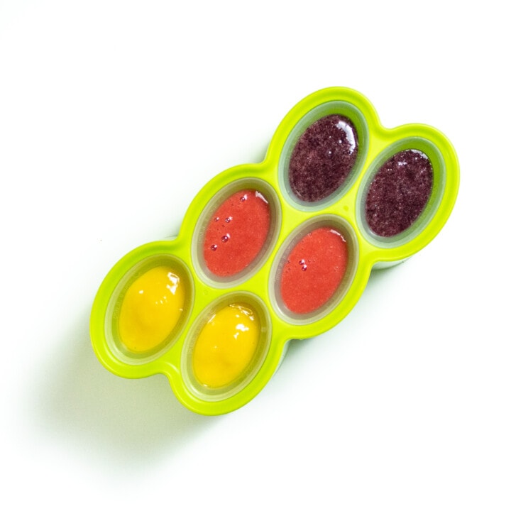 A green popsicle mold full of 3 different popsicle flavors.