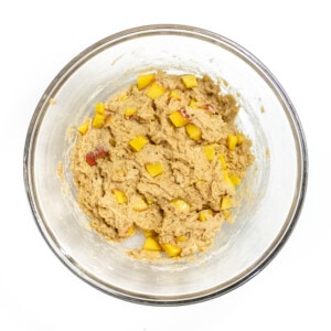 A clear bowl full of peach muffin batter.