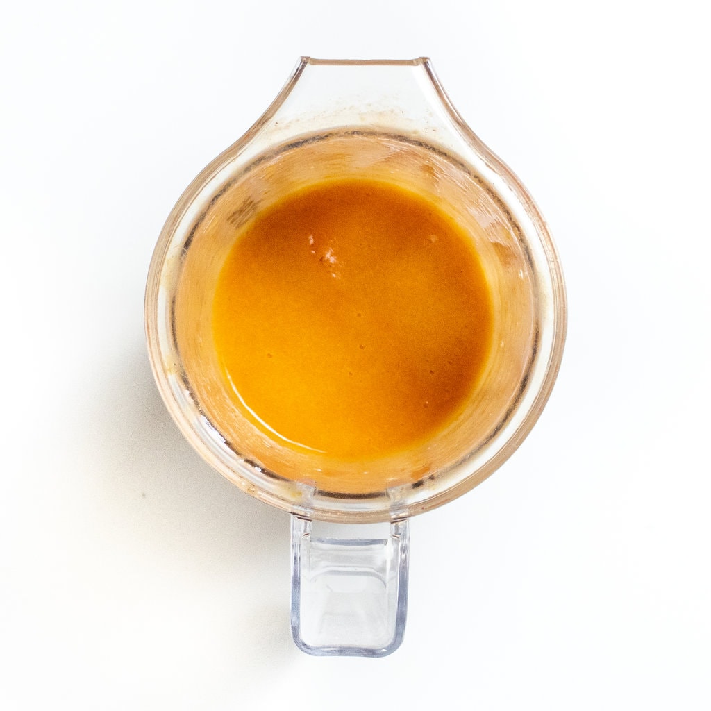 Nectarine purée in a clear blender on a white countertop.