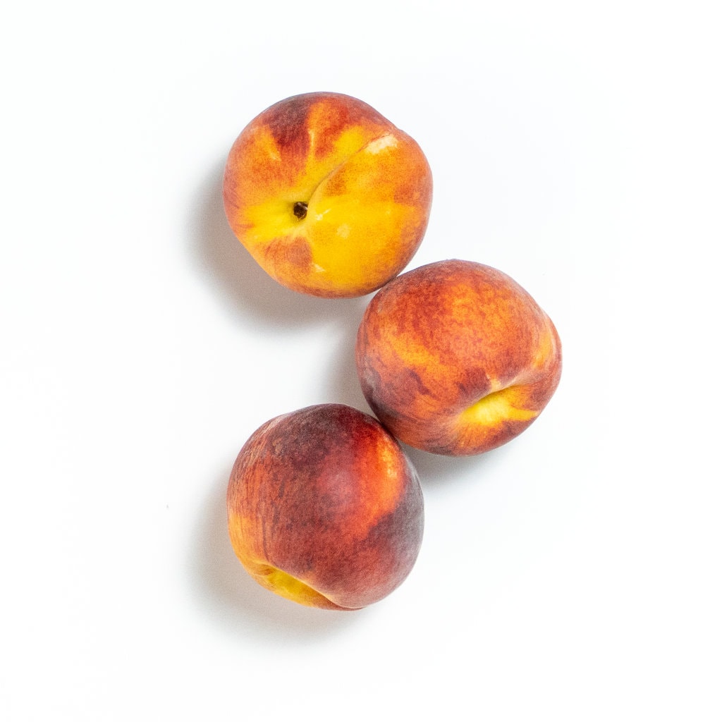 3 whole peaches on a white background. 