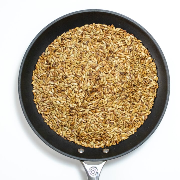 A skillet on a white countertop full of toasted sunflower seeds.