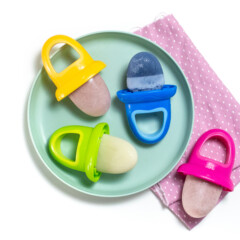 Teal baby plate with different flavors of breast milk popsicles on colorful popsicle sticks.