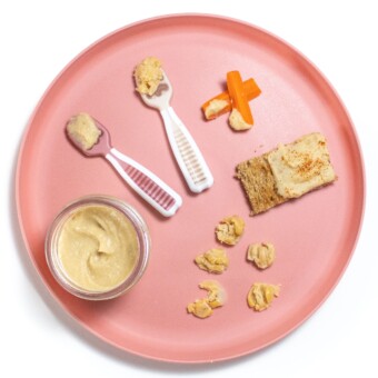 Pink baby plate with different ways to serve chickpeas to baby, including a puree and finger foods.