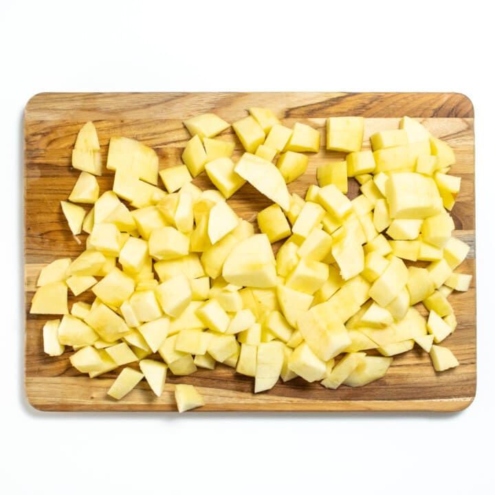 Wooden cutting board with chopped apples.