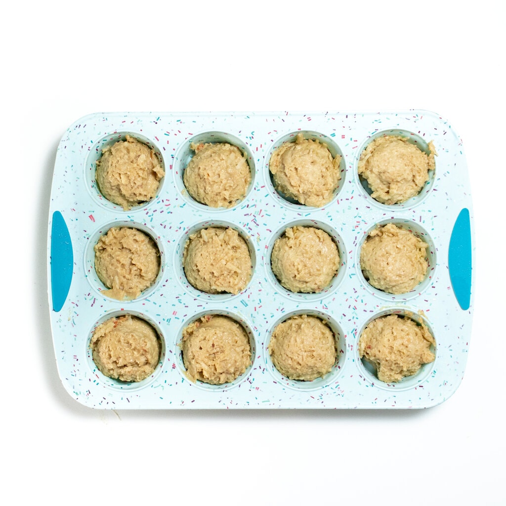 Blue muffin tin on a white countertop with apple muffins inside.