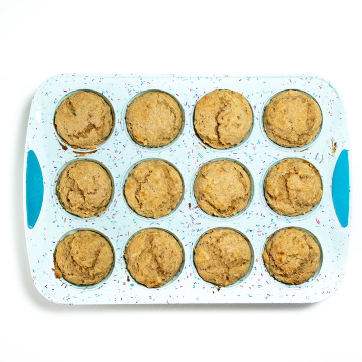 Blue muffin tin with cooked apple muffins.