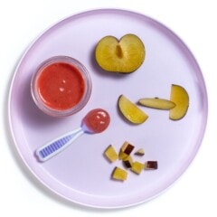 Purple baby plate with several different ways to cut and serve plums to your baby.