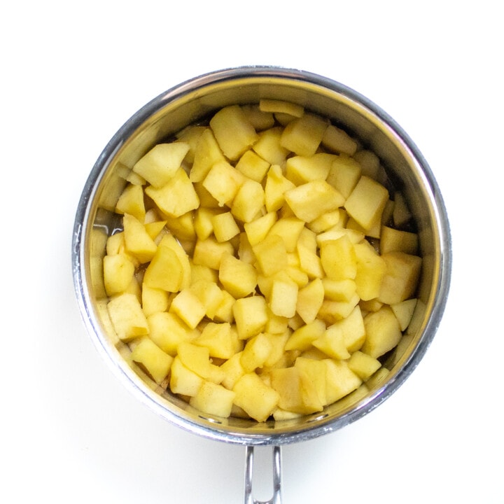 Silver saucepan filled with cooked chunks of apples.