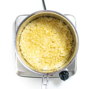 Cooked rice with seasoning in a silver saucepan on a white counter.