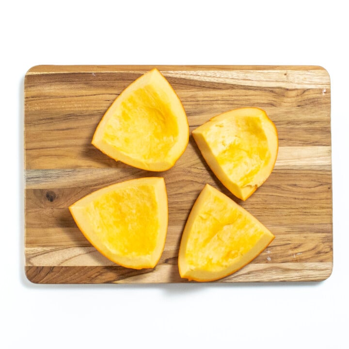 A wooden cutting board with chunks of pumpkin.