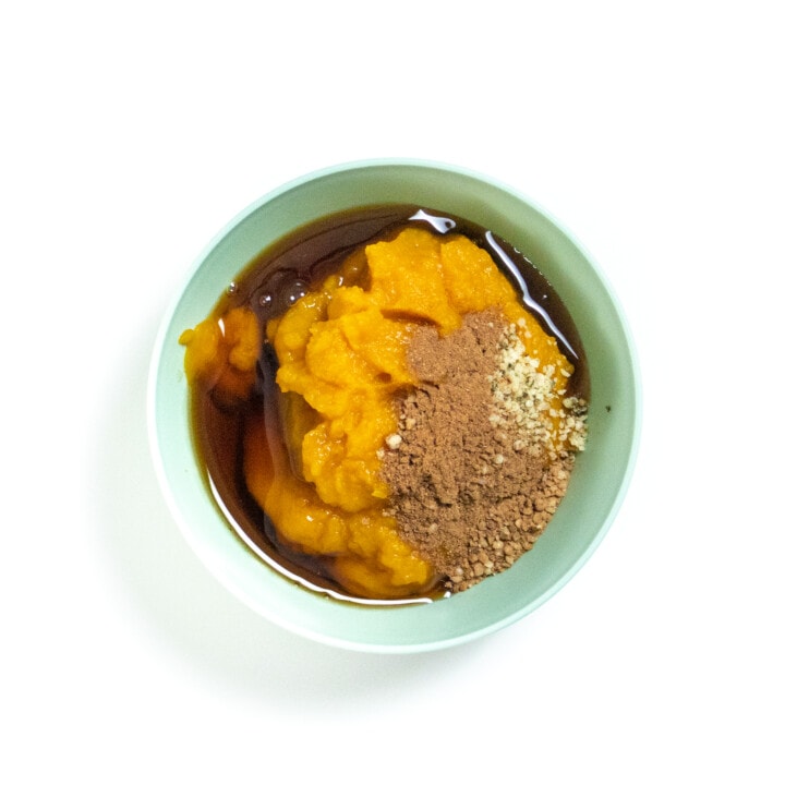 Teal baby bowl, full of pumpkin purée, spices, hemp seeds, and maple syrup.