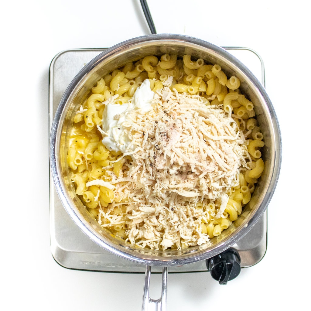 Silver sauce, pan, full of cooked noodles, yogurt, and shredded chicken.
