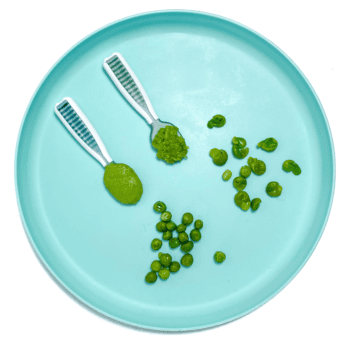 Blue baby play with two spoons of pure pea, purée and mash peas, flatten the peas in a hole peas for baby led weaning.