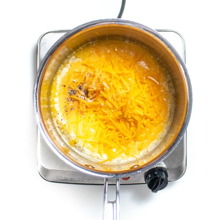 A silver sauce, pan with melted butter, shredded cheese, and salt and pepper.