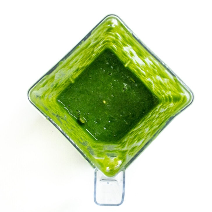 Clear blender on a white countertop with puréed, spinach, and green bean purée for Baby.