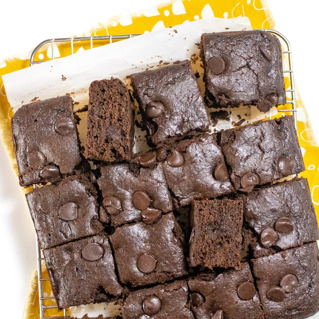 Cooling rack with cut, sweet potato, brownie squares on a white countertop with a yellow patterned napkin.