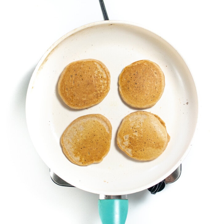 White skillet with golden brown whole wheat pancakes.