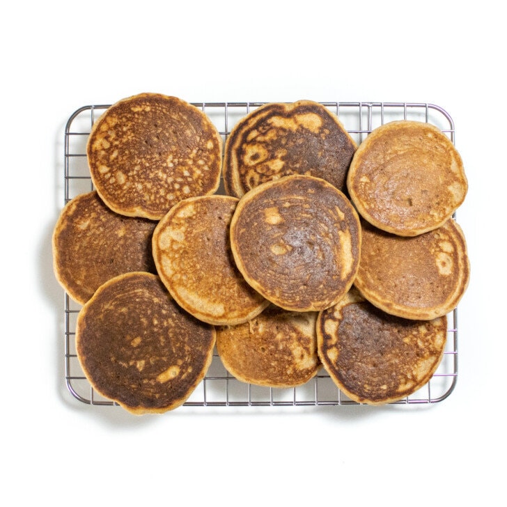 Silver cooling rack on a white countertop with golden brown whole wheat pancakes.