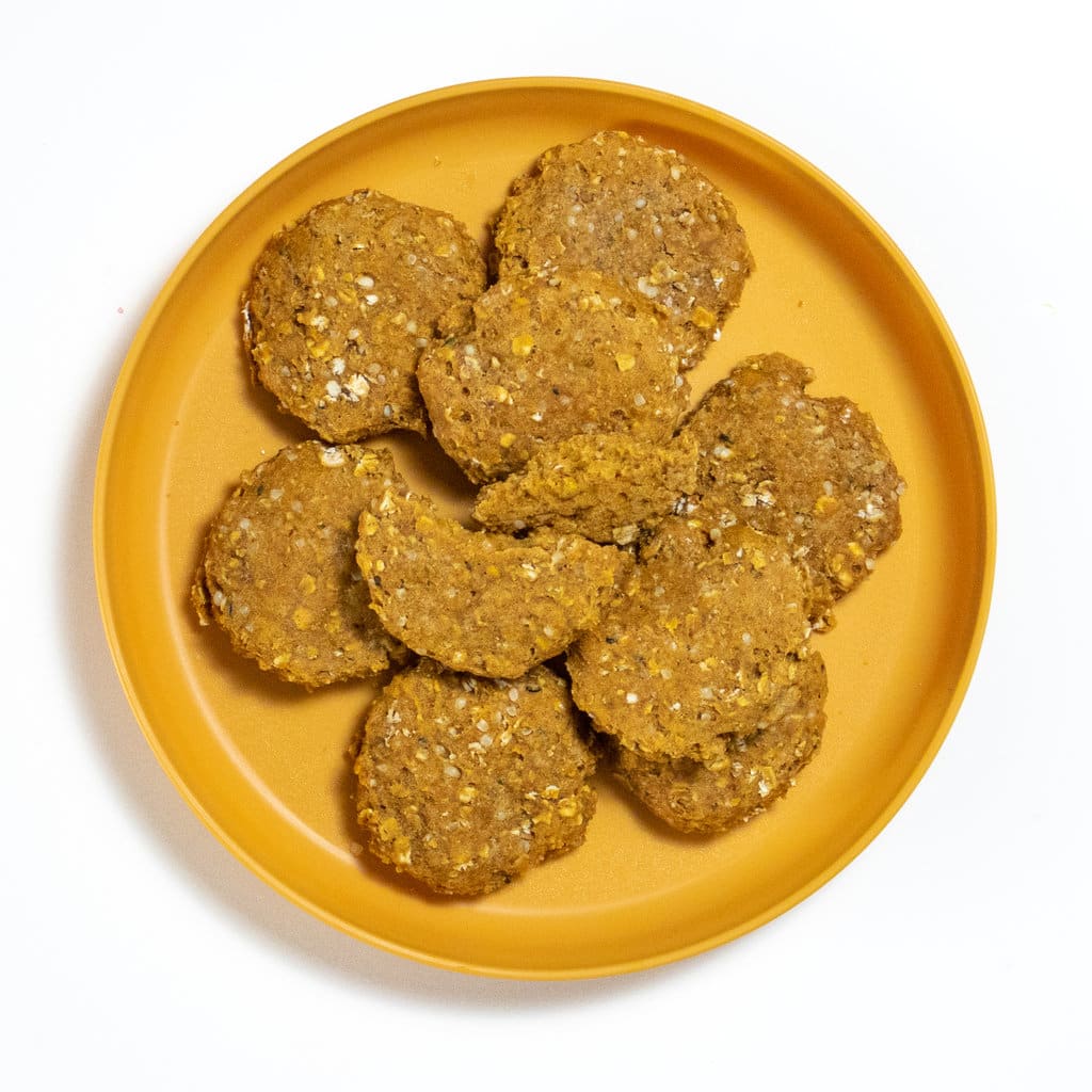 Mustard colored dollar plate with baby cookies on top with one cut in half.