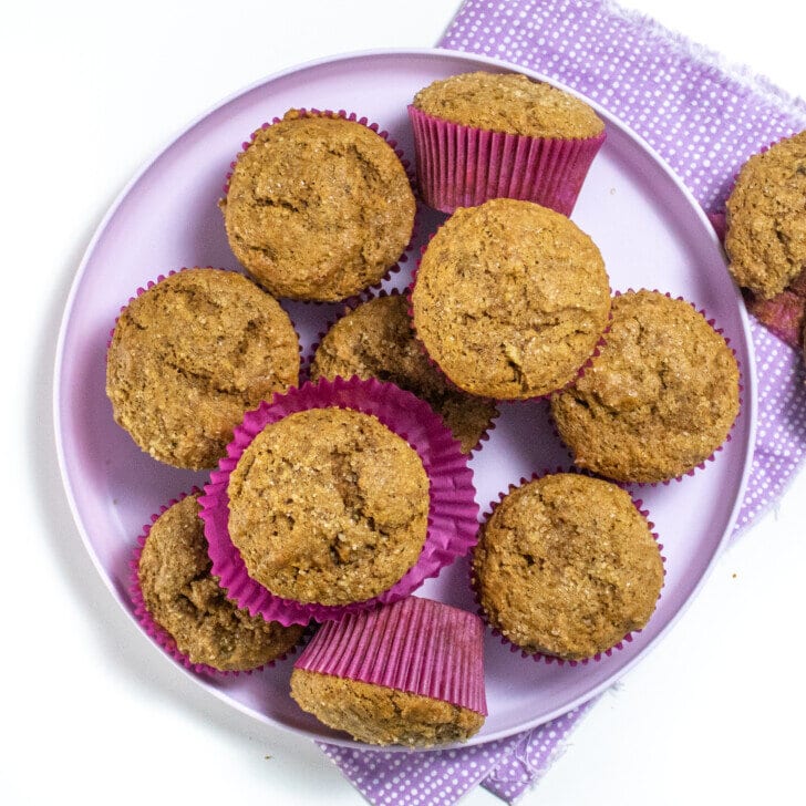 Purple kids plate on a purple napkin with stacks of gingerbread muffins in purple wrappers.