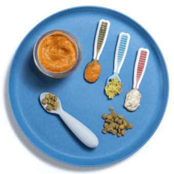 Blue baby plate with different ways to show baby how to eat lentils as a puree or solid food. Plate is on a white counter.