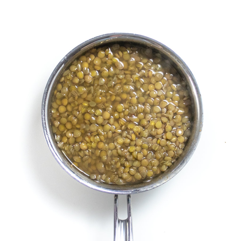 Medium silver saucepan with cooked lentils.