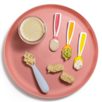 A pink baby plate on the white countertop, showing different ways to serve quinoa to Baby, including a purée, chunky or finger foods.