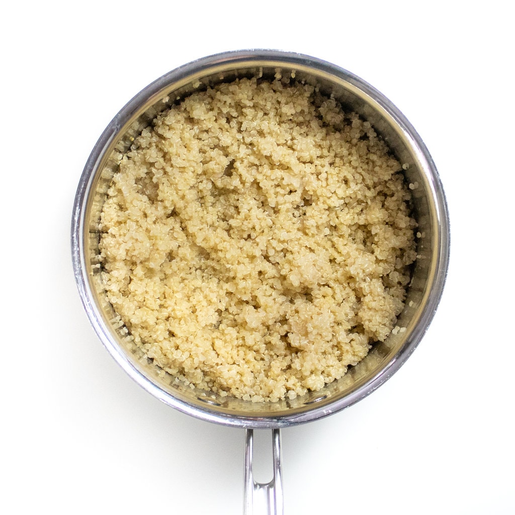 A silver sauce pan with cooked and fluffed quinoa.