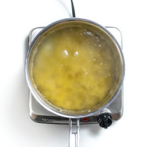 A silver sauce, pan with boiling water and pasta.