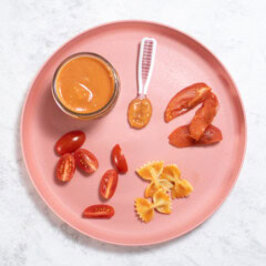 Pink baby plate on my white kitchen counter showing different ways to serve tomatoes to baby.