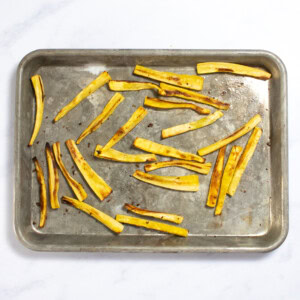 roasted strips of parsnips on a baking sheet, cooling.