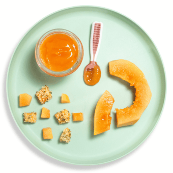 Teal baby plate on a white background showing how to serve papaya to baby.