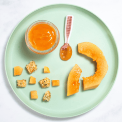 Teal blue kids plate sitting on my white marble counter with papaya cut and pureed in different shapes and textures for baby.