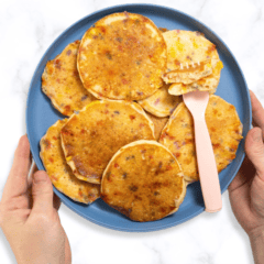 Two hands holding a blue kids plate full of funfetti pancakes.
