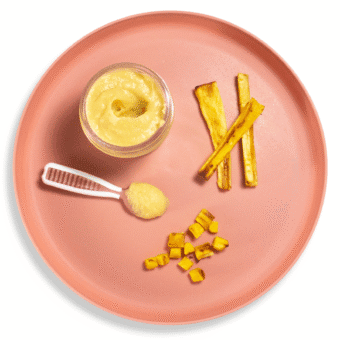 Pink baby plate on a white background with different ways to serve parsnips to your baby - puree, strips for baby-led weaning and chopped for finger foods.