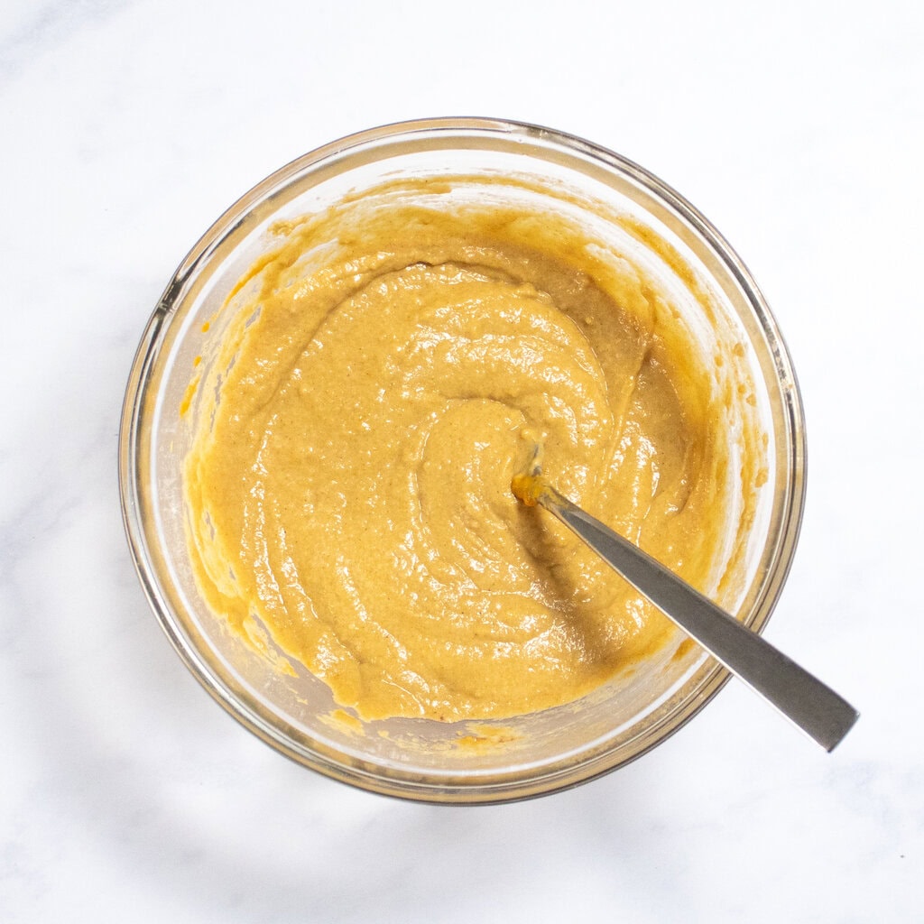 Clear class bowl with whisked pancake ingredients inside. 