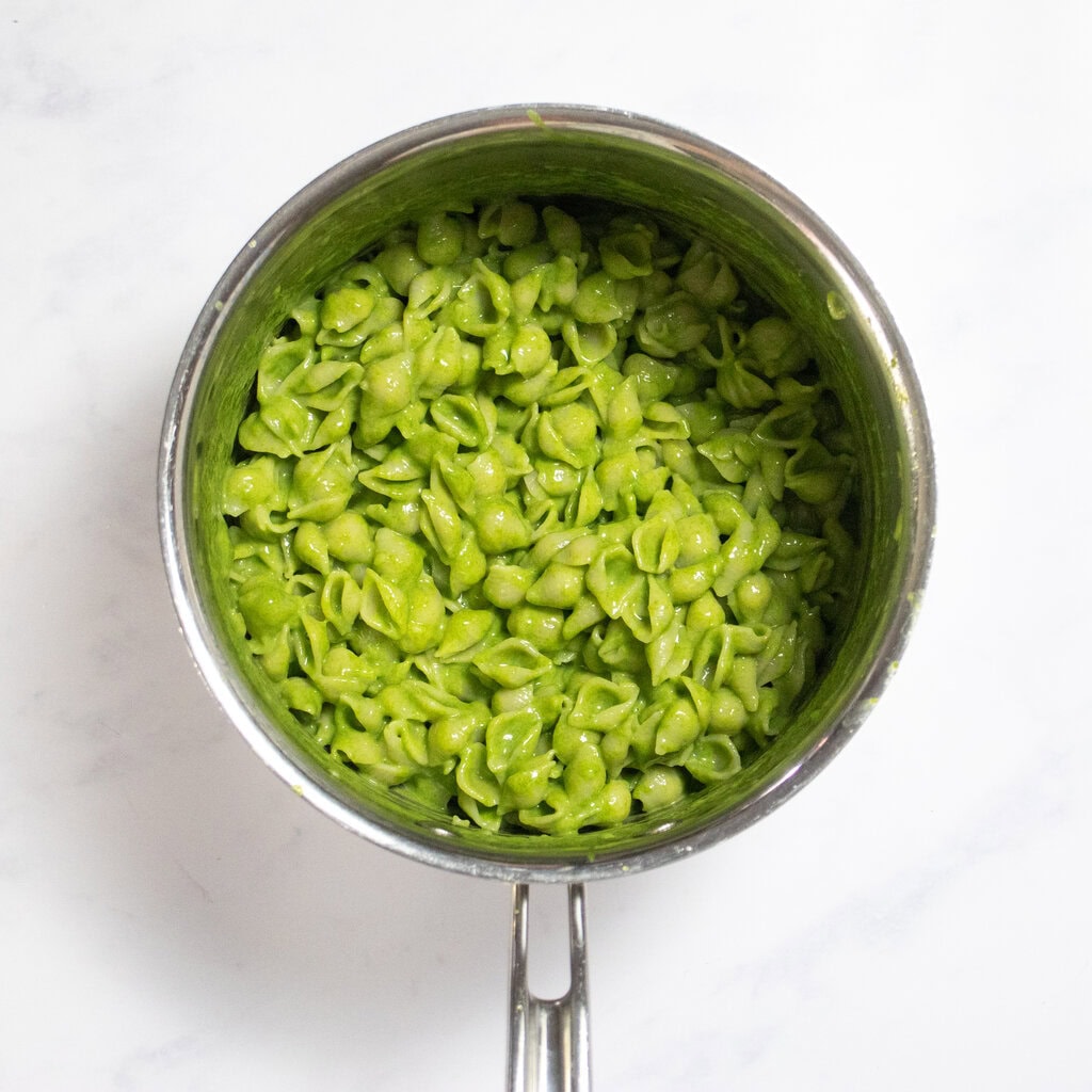 Medium saucepan with the green spinach mac and cheese inside, sitting on my kitchen counter.