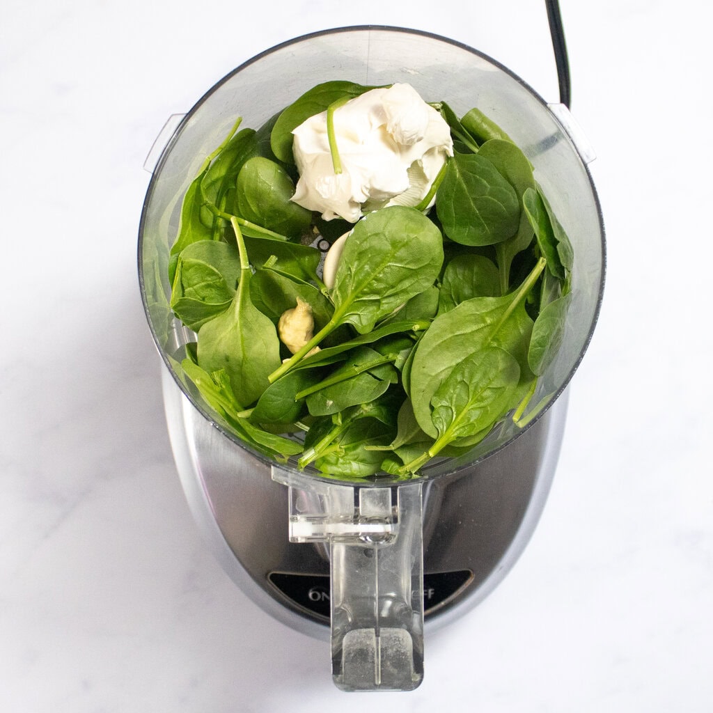 A food processor on my kitchen counter with ingredients for the spinach mixture.