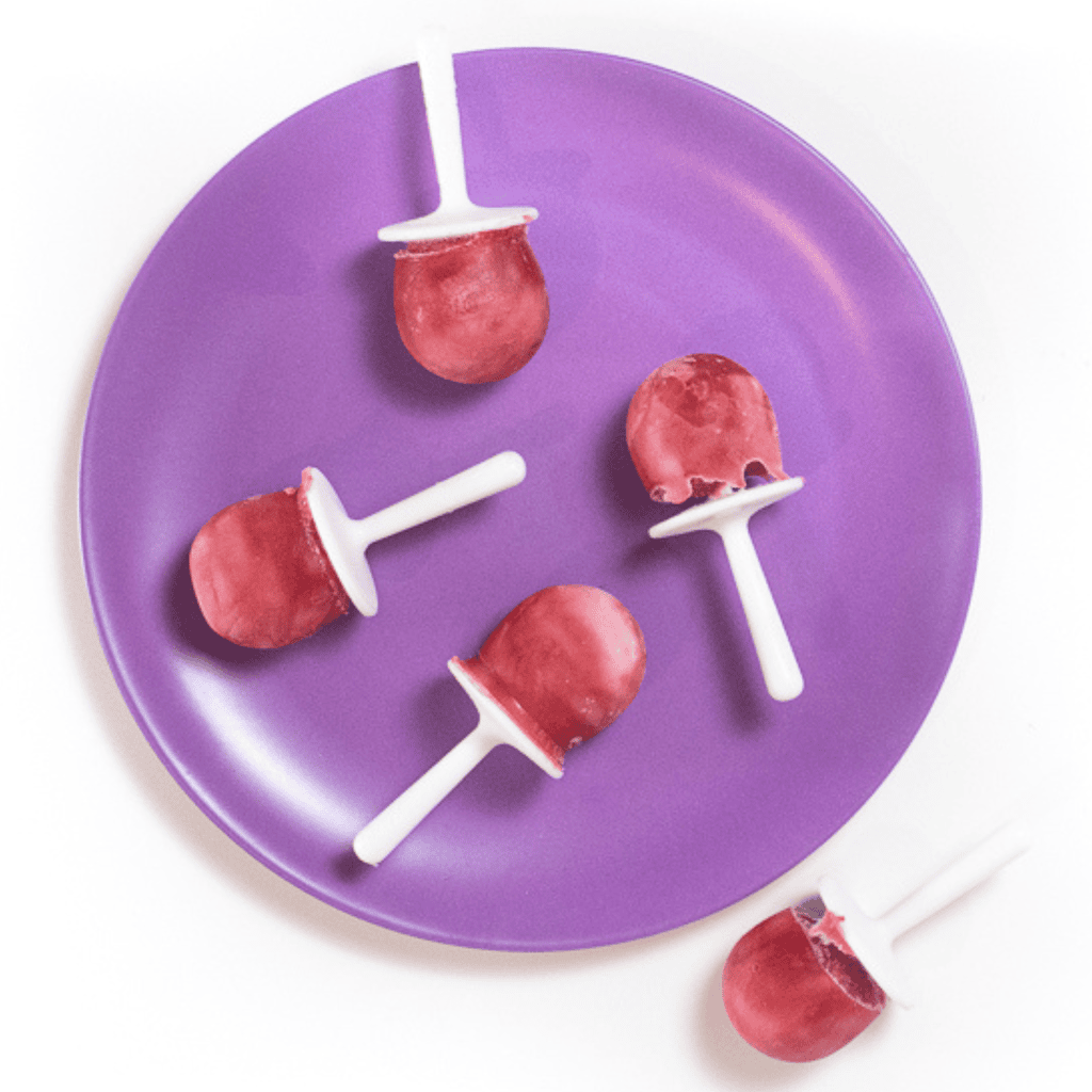Purple kids plate with raspberry and yogurt popsicles on top. Sitting on a white counter.