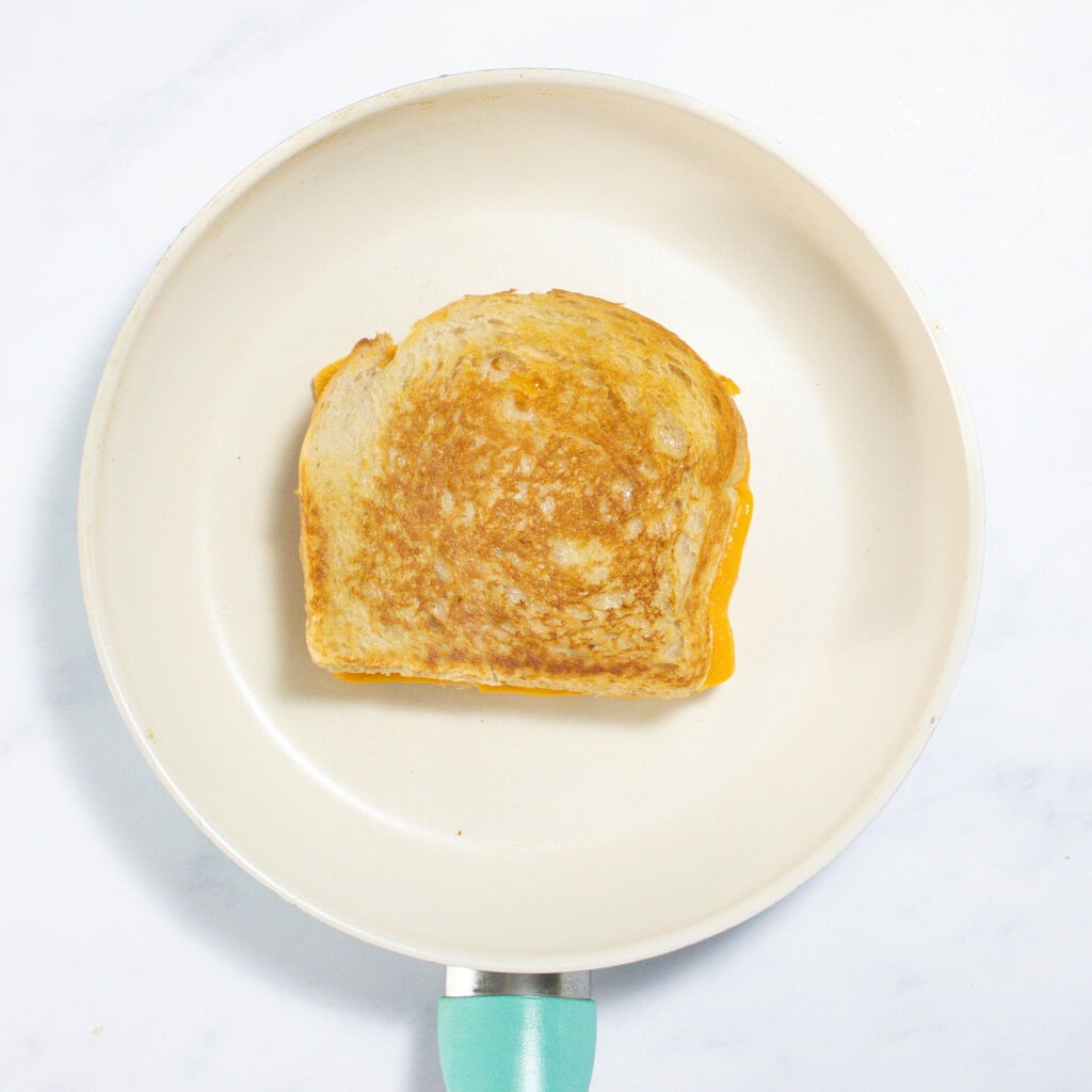 A white skillet with a crispy veggie grilled cheese.